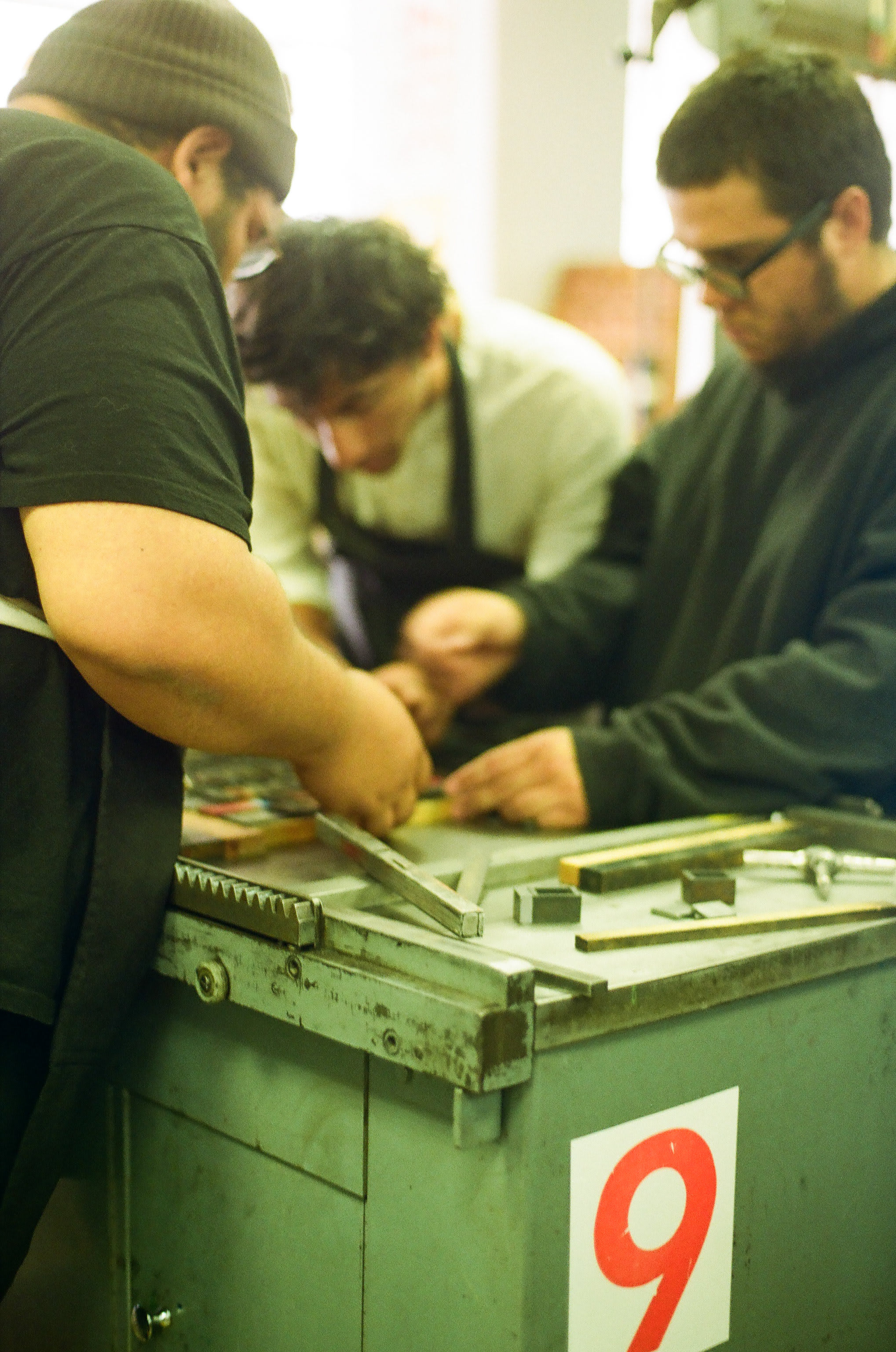 A few pressman gathered around the letterpress to set the composition