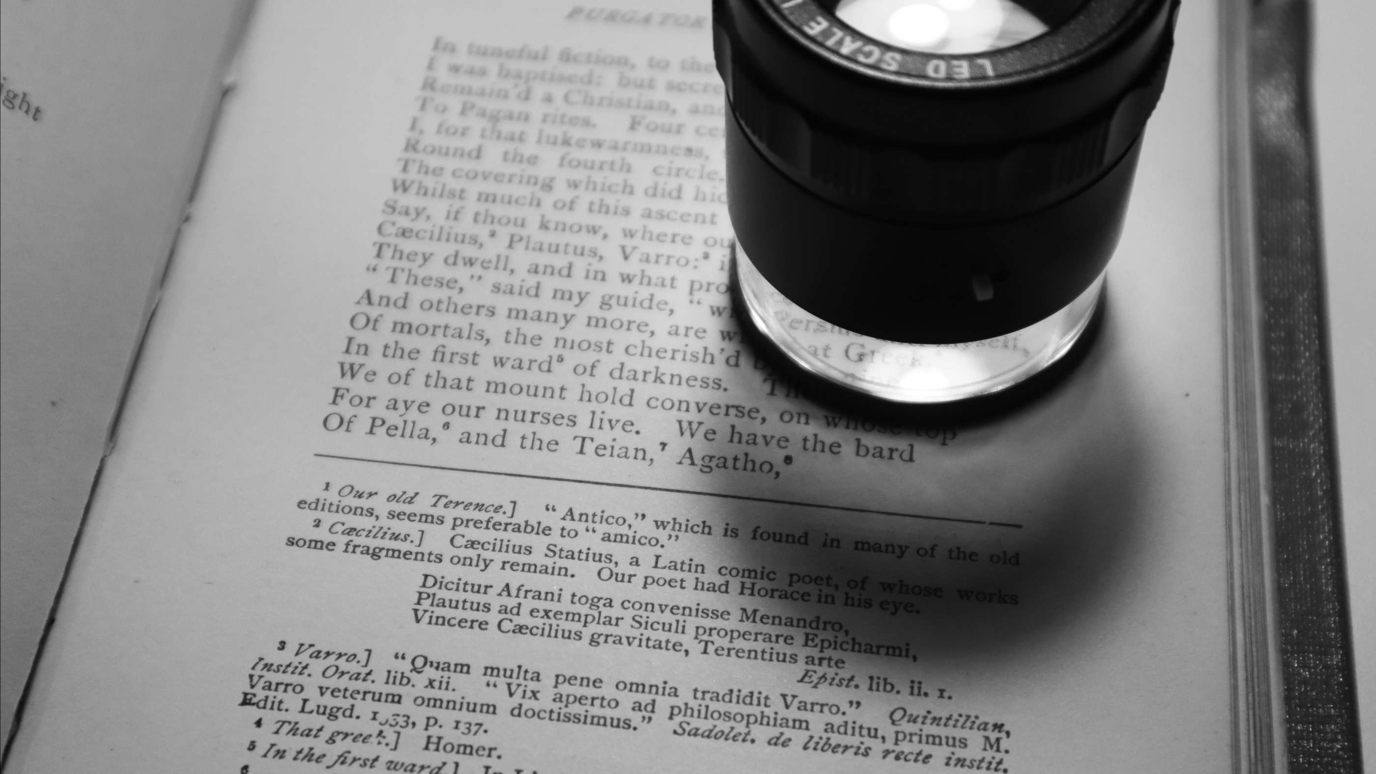 Photograph of a 10x micro lens / loupe on top of a page of Dante's Pergatory.