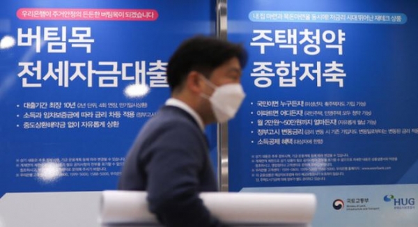 버팀목 전세자금대출과 주택청약 통합저축을 안내하는 정부 포스터 앞을 시민이 지나가는 장면