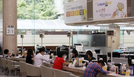 은행 창구에서 여러 명의 고객들이 대출 상담과 금융 업무를 기다리고 있는 모습