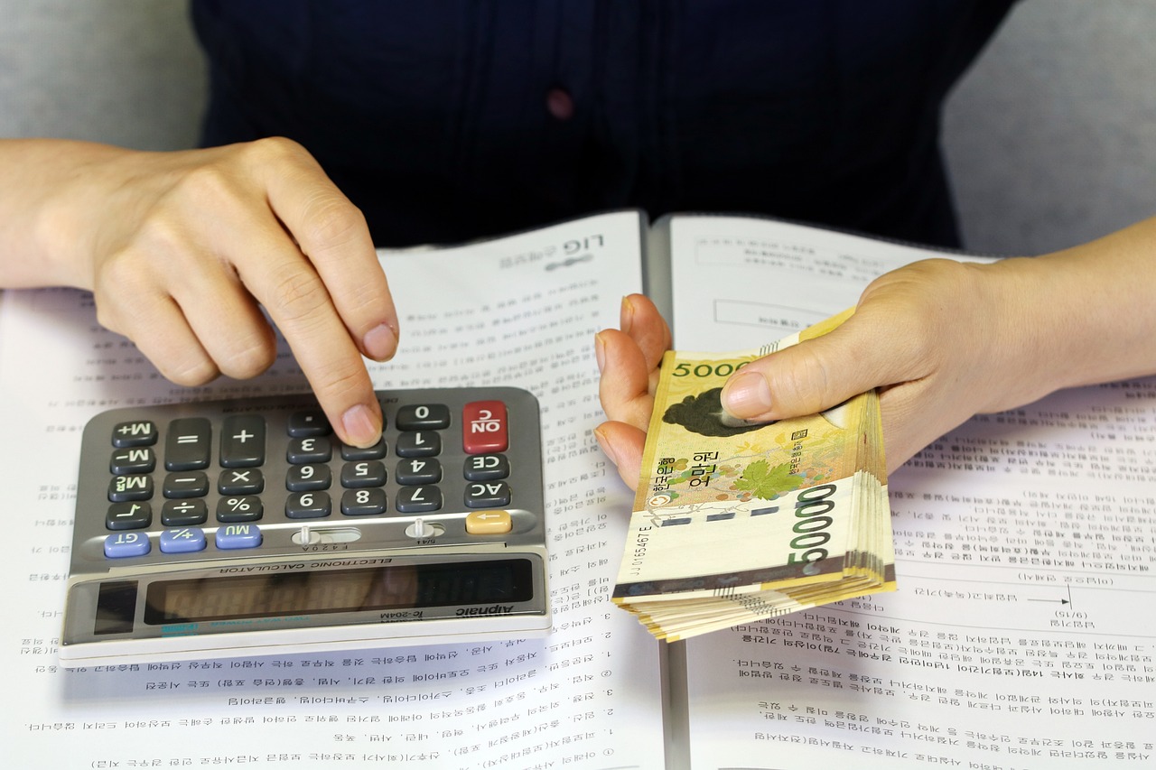 한국 지폐를 들고 계산기로 금액을 계산하는 모습