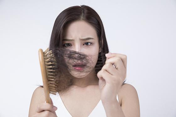 빗에 엉켜 빠진 머리카락을 보고 탈모를 걱정하는 여성의 모습