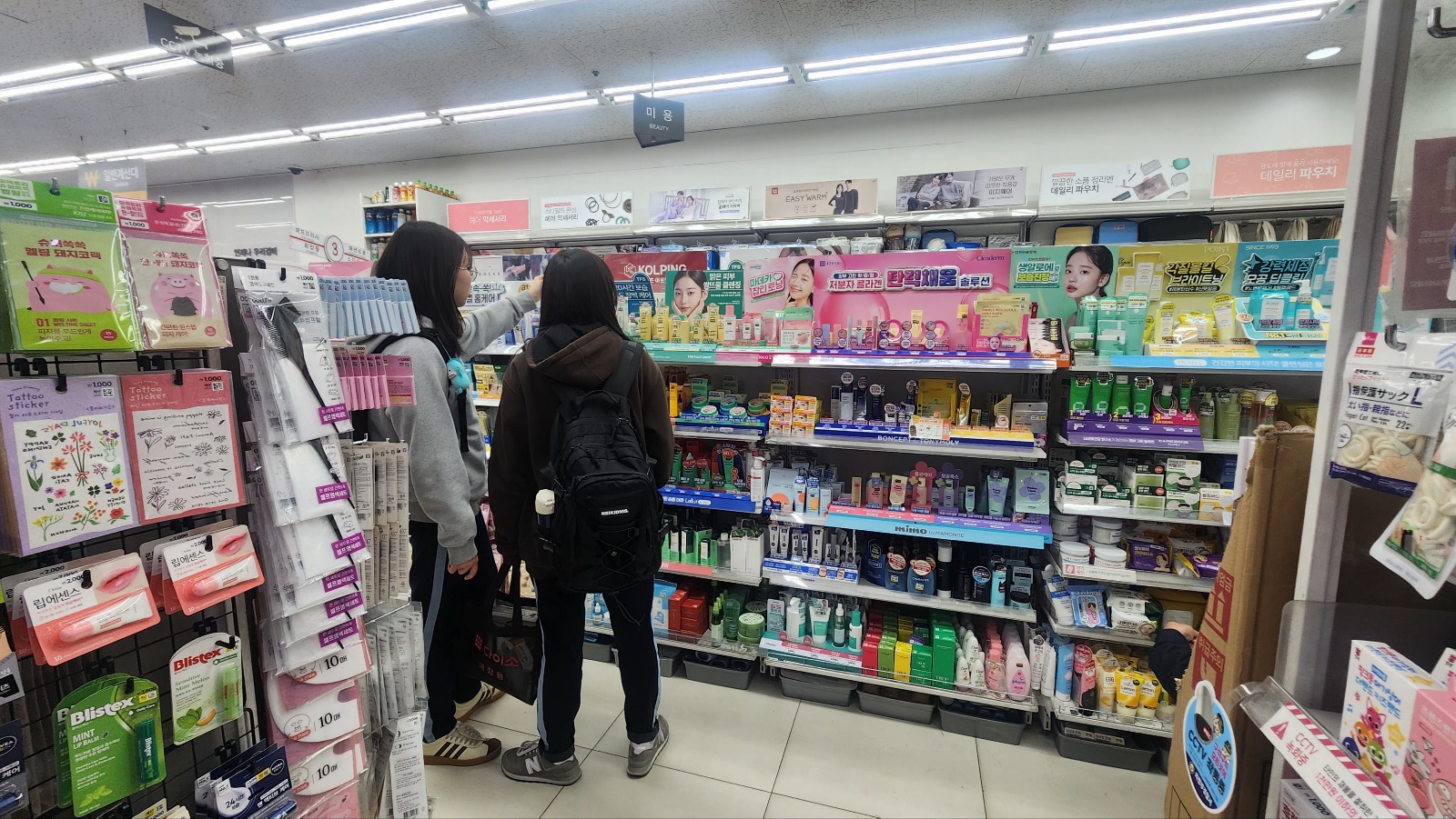 다이소 매장 뷰티 코너에서 고객들이 제품을 살펴보는 모습, 국민가게 다이소의 1000원으로 4조원을 만든 성공 비밀을 설명하는 글에 적합한 이미지