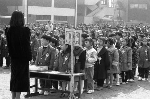 1970년대 국민학교 운동장에서 교사 앞에 줄지어 선 아이들, 조회·입학식 풍경을 담은 흑백 사진—시니어 추억 회상 레트로 이미지