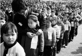 1970년대 국민학교 운동장에서 교사가 아이들의 명찰을 달아 주며 줄을 세우는 입학식 풍경을 담은 흑백 사진—시니어 추억 레트로 이미지