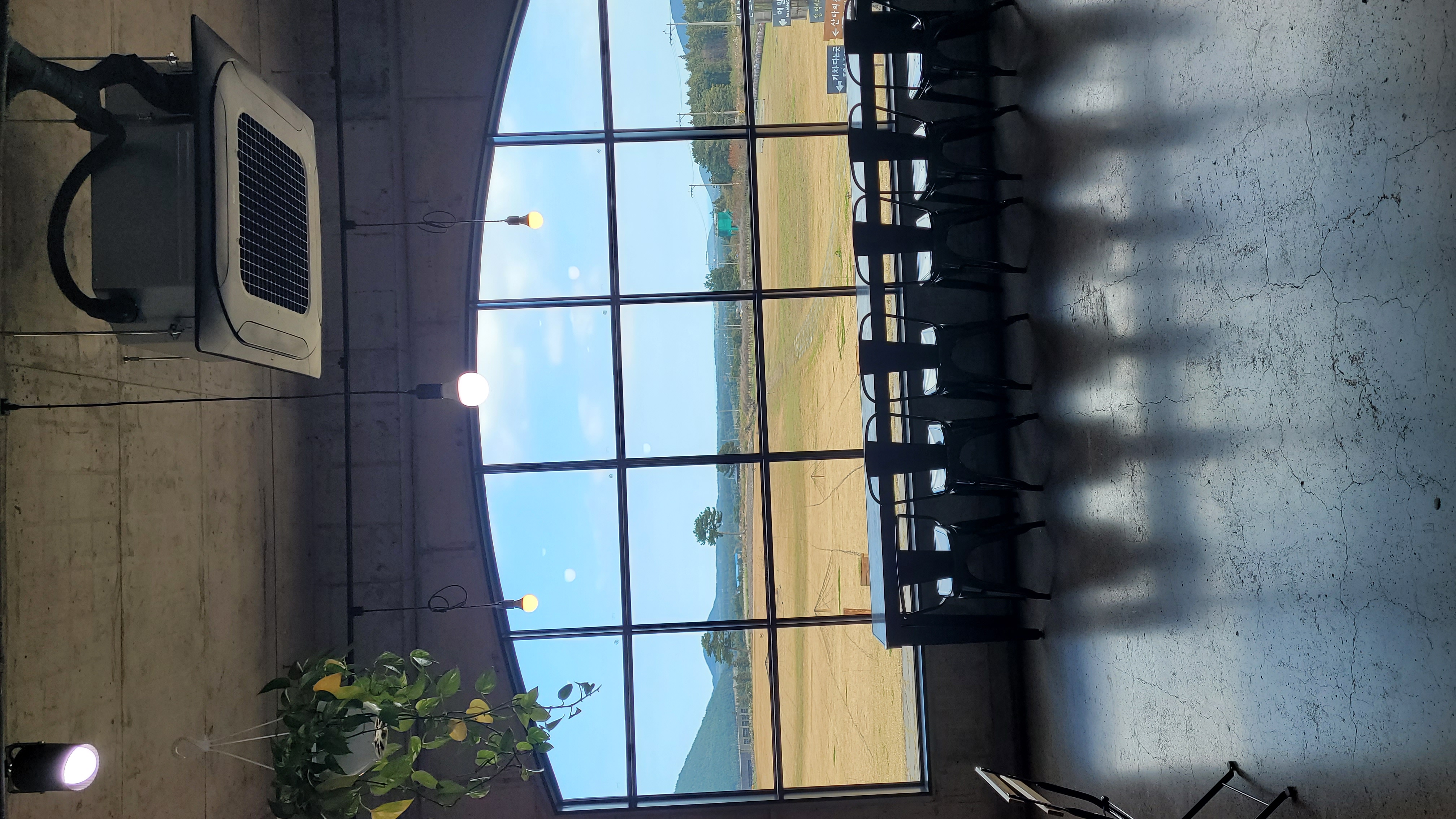 제주 보롬왓 카페 홀의 아치형 대형 창문, 창밖으로 펼쳐진 제주 들판과 오름 전망