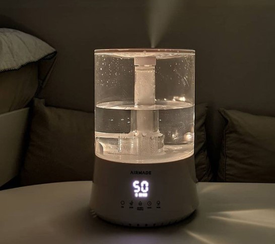 에어메이드 AMH-7000 복합식 가습기 실제 작동 모습 - 투명 수조와 디지털 습도 표시 50% 화면이 보이는 야간 사용 장면