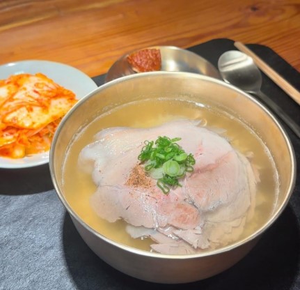 옥동식 미쉐린 돼지곰탕 맑은 국물과 얇게 썬 돼지고기가 황금 놋그릇에 담긴 모습, 김치와 반찬이 함께 제공되는 합정 맛집 대표 메뉴