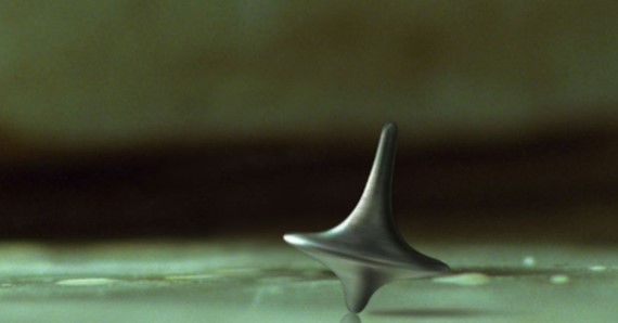 인셉션 결말 장면에서 바닥 위를 멈추지 않고 계속 돌아가는 금속 팽이 토템 클로즈업 스틸컷으로 현실과 꿈의 경계를 상징하는 핵심 이미지