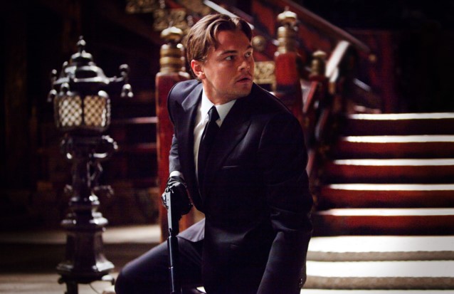 인셉션 코브가 꿈속 화려한 계단 앞에서 총을 들고 긴장한 채 무릎을 꿇고 있는 장면 - 현실과 꿈의 경계에서 갈등하는 코브의 모습