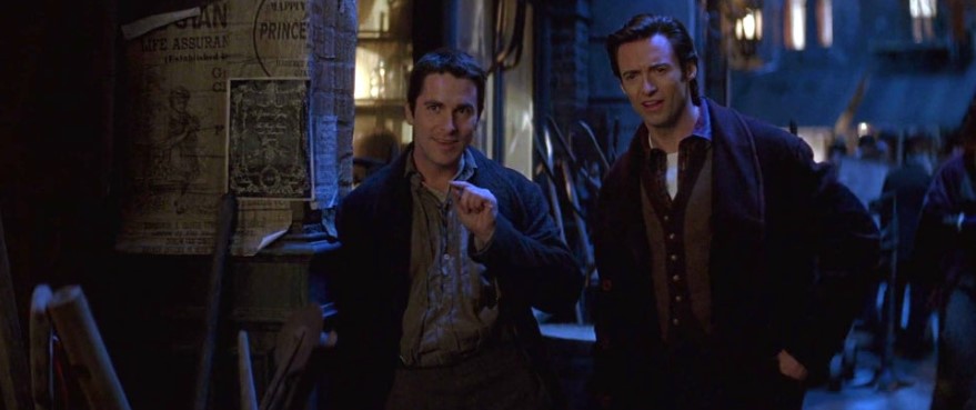 영화 프레스티지 스틸컷 – 젊은 시절 보든과 앤지어가 야간 거리에서 나란히 서 웃고 있는 우정과 경쟁의 시작을 보여주는 장면