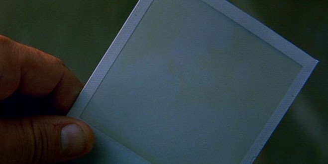 메멘토 영화 오프닝 스틸컷 - 폴라로이드 사진이 현상되는 것이 아니라 역순으로 지워지는 첫 장면, 레너드의 기억 삭제를 상징하는 핵심 복선