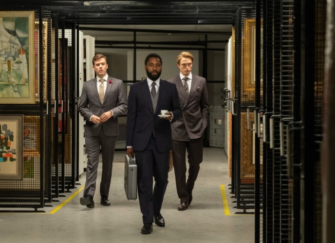 테넷 오슬로 프리포트 침투 장면 - 주도자(존 데이비드 워싱턴)가 중앙에서 당당하게 앞장서고 양옆으로 두 요원이 함께 미술품 보관 창고를 걸어오는 장면. 테넷의 핵심 작전 공간인 오슬로 프리포트에서 정방향과 역방향의 두 시간이 교차하는 인버전의 비밀이 숨겨진 공간으로 향하는 결정적 장면