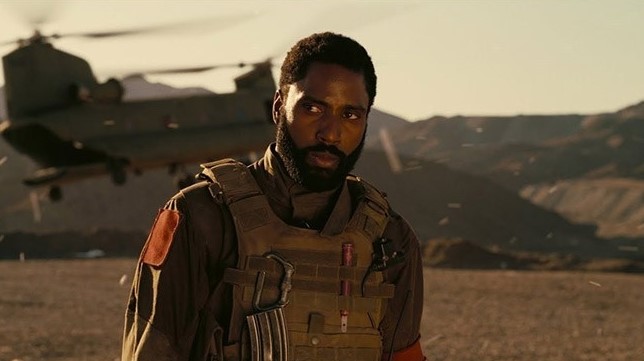 테넷 스탈스크-12 최종 작전 장면 - 주도자(존 데이비드 워싱턴)가 전투 방탄복을 착용하고 헬리콥터가 보이는 황야에서 결연한 표정으로 서 있는 장면. 정방향 팀과 역방향 팀이 동시에 투입되어 알고리즘 무기를 막기 위한 테넷 최후의 결전, 스탈스크-12 작전의 핵심 장면