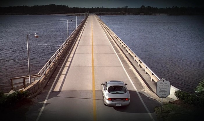 트루먼 쇼 탈출 시도 장면 - 트루먼이 시헤이븐 섬을 떠나는 다리 위에서 물 공포증으로 멈춰 서는 장면, 오른쪽에 You Are Now Leaving Seahaven Island 표지판