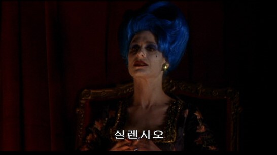 영화 멀홀랜드 드라이브의 마지막 장면. 실렌시오 극장 박스석의 파란 머리 여성이 '실렌시오'라고 속삭이는 모습. 결말 해석의 핵심 상징이자 침묵의 선언.