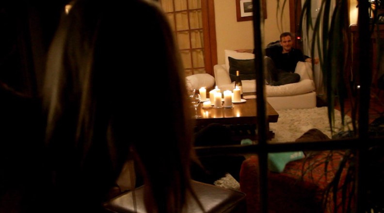 영화 평행이론 도플갱어 살인 코히어런스 스틸컷 - 정전 후 촛불만 켜진 어두운 거실에서 창문 너머 다른 우주의 인물을 몰래 관찰하는 장면
