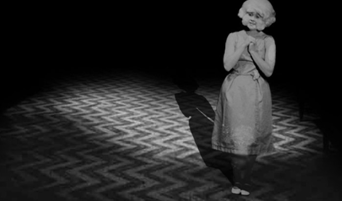 이레이저헤드(1977) 라디에이터 여인(Lady in the Radiator)이 지그재그 무늬 바닥 위에서 노래하는 스틸컷 — 헨리의 도피처이자 천국을 상징하는 핵심 장면