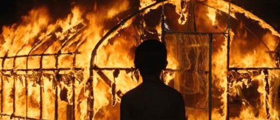 영화 버닝 스틸컷 — 꿈속에서 비닐하우스가 불타는 장면을 바라보는 어린 종수의 뒷모습