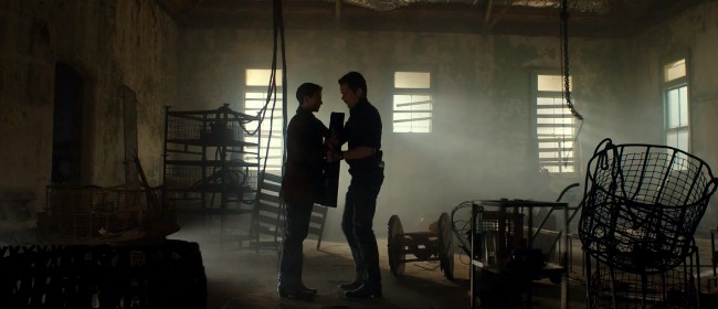 영화 타임 패러독스에서 두 인물이 마주 보고 서 있는 미장센이 돋보이는 실내 스틸컷 장면