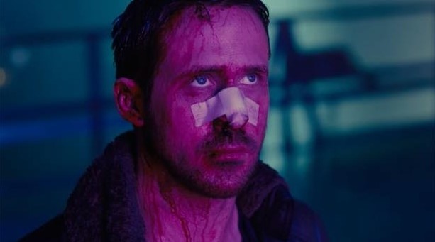 블레이드 러너 2049 스틸컷 — 자신이 특별한 존재가 아님을 알게 된 K(라이언 고슬링)의 절망적인 표정, 보라빛 네온 조명