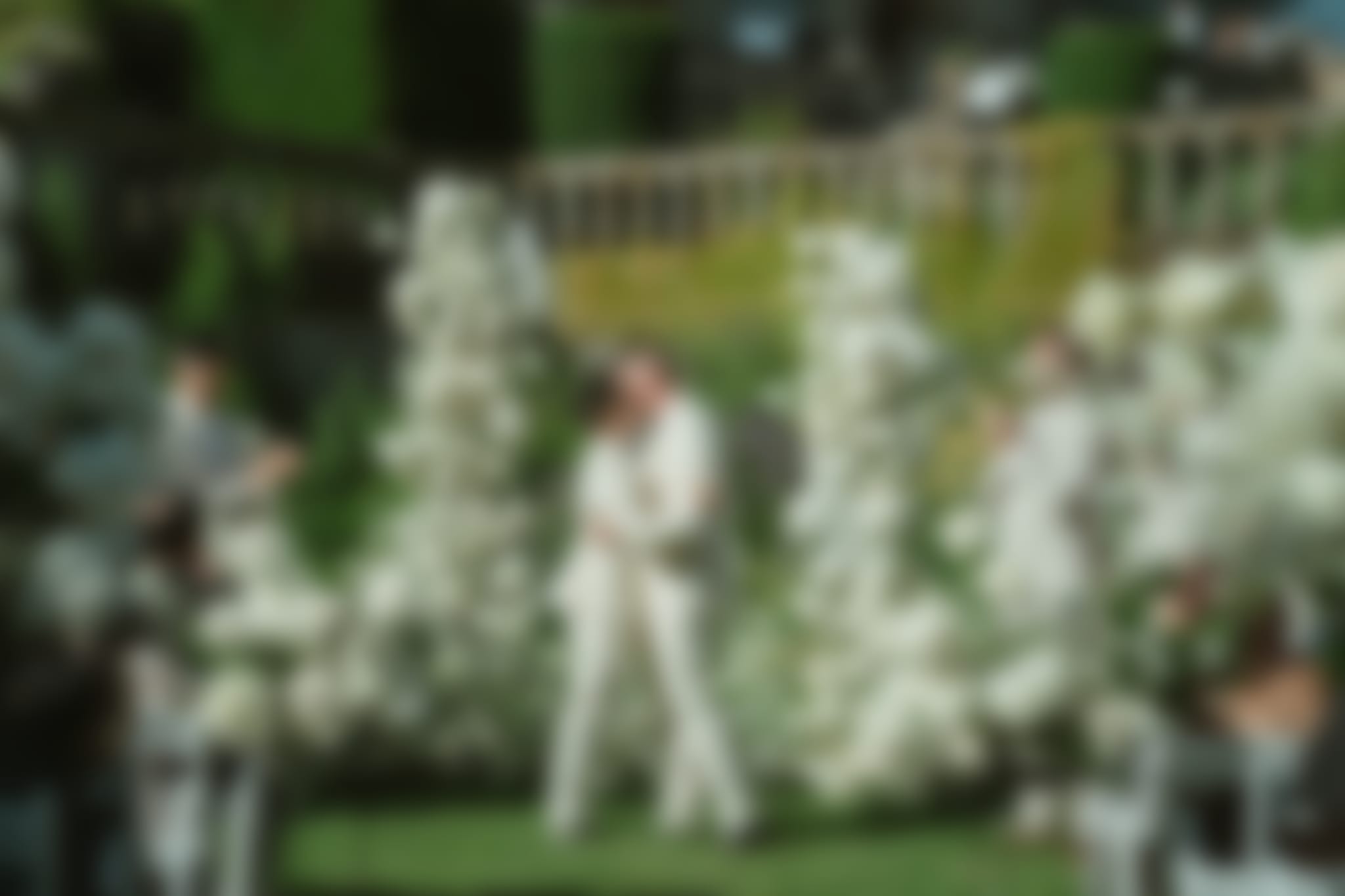 Two grooms sharing their first kiss at Hatley Castle altar, surrounded by white florals and cheering guests