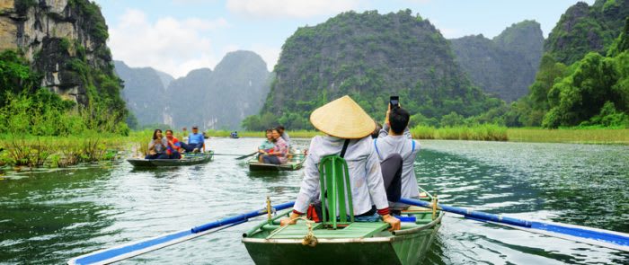 Tourists in boats. Rowers using feet to propel oars, Vietnam