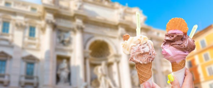 Famous landmark fountain di Trevi in Rome, Italy during summer sunny day with italian ice cream gelato in the foreground.