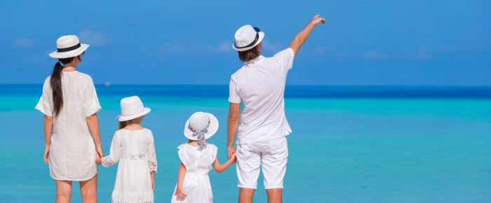 Happy family of four on white beach vacation