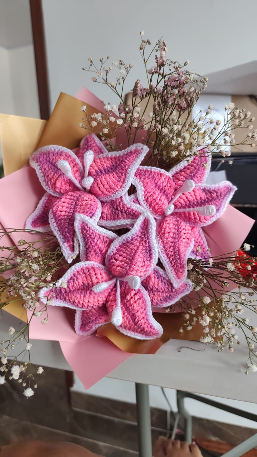Arreglo floral botánico tejido a mano compuesto por orquídeas de crochet color lila claro con detalles morados y amarillos en el centro, acompañadas de texturizadas ramas de lavanda púrpura. El hermoso regalo está envuelto en papel floristero lila mate y atado con una elegante cinta color crema con la palabra 'Love'.