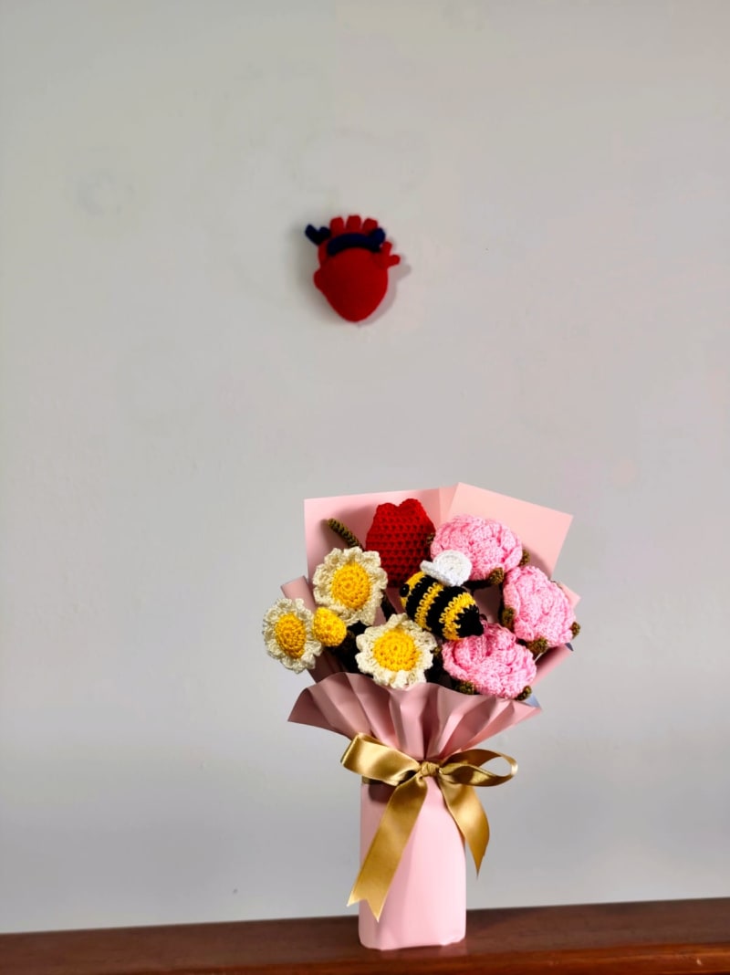 Super Bouquet Nuditos: Un gran ramo mixto con margaritas blancas, flores rosa pastel, un corazón rojo tejido y una abeja amigurumi, envuelto en papel rosa premium con cinta dorada.