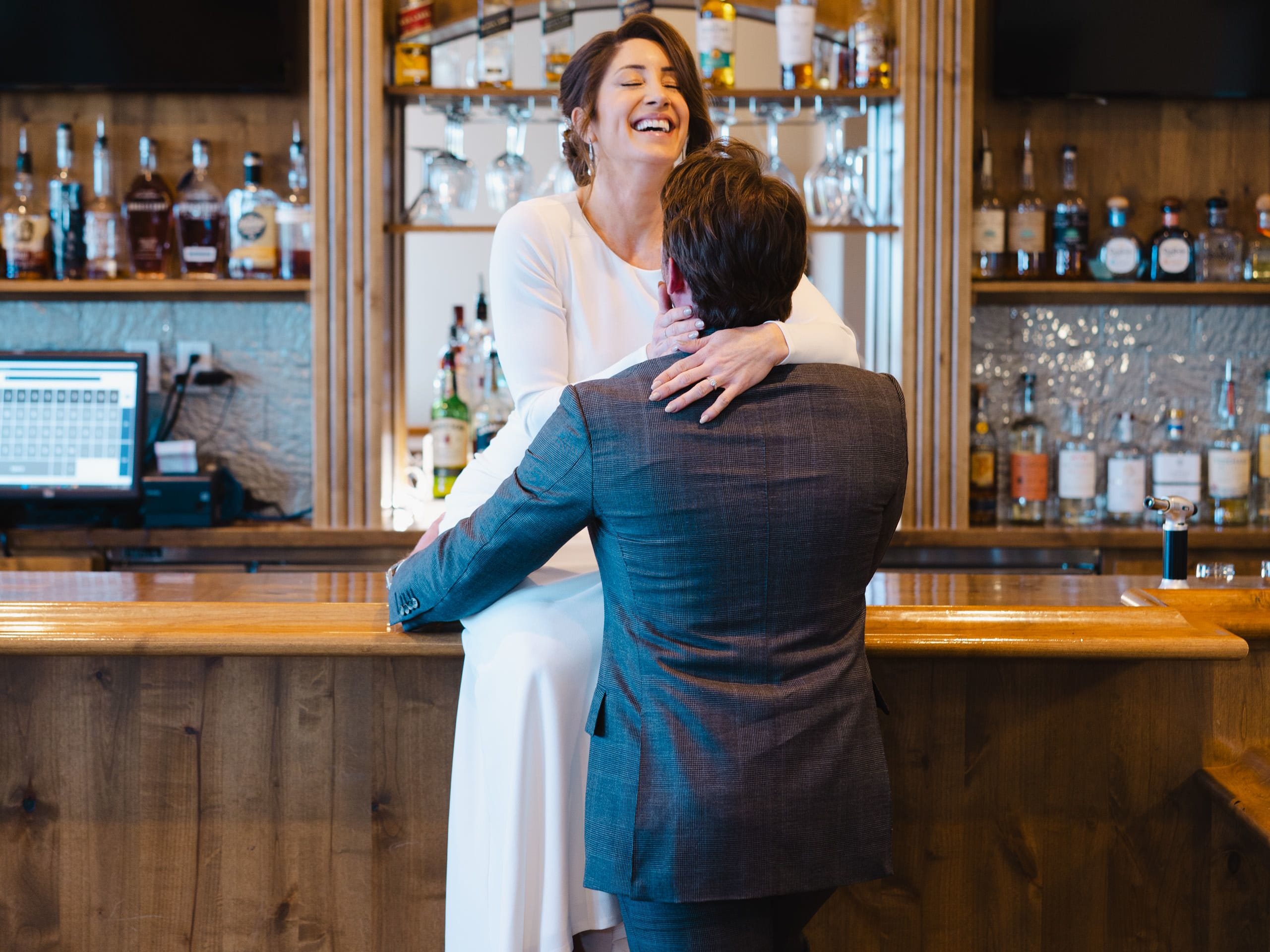 wedding couple sitting on a bar below a neon sign