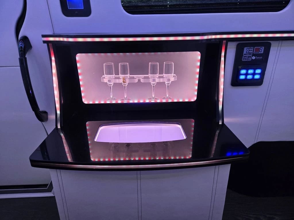 Mercedes-Benz Sprinter limo van interior with bar, lounge seating, and ambient lighting