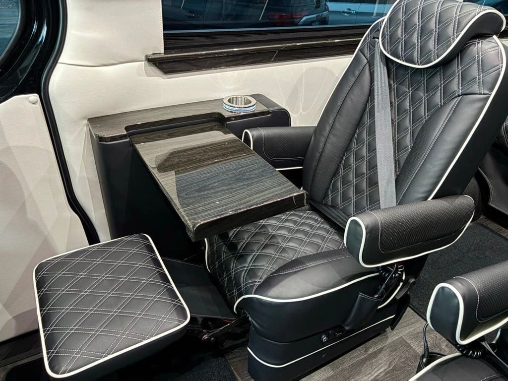 Luxury Sprinter van interior with diamond-stitched leather seating and custom woodwork