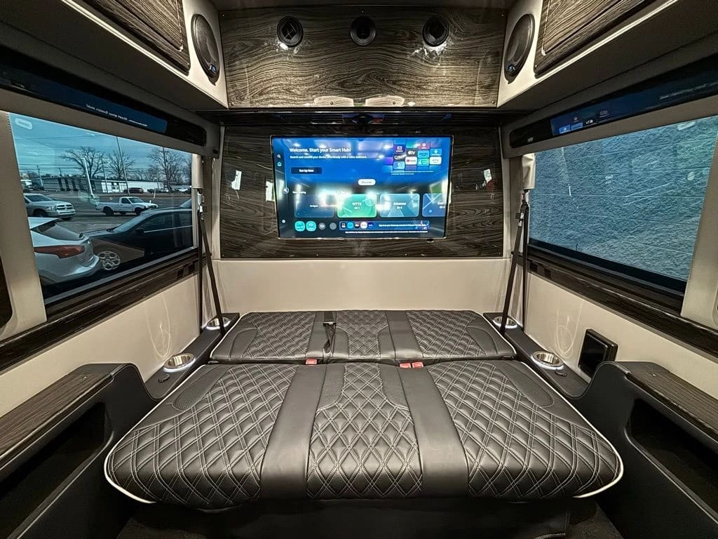 Luxury Sprinter van rear entertainment center with HDTV and diamond-stitched leather bench