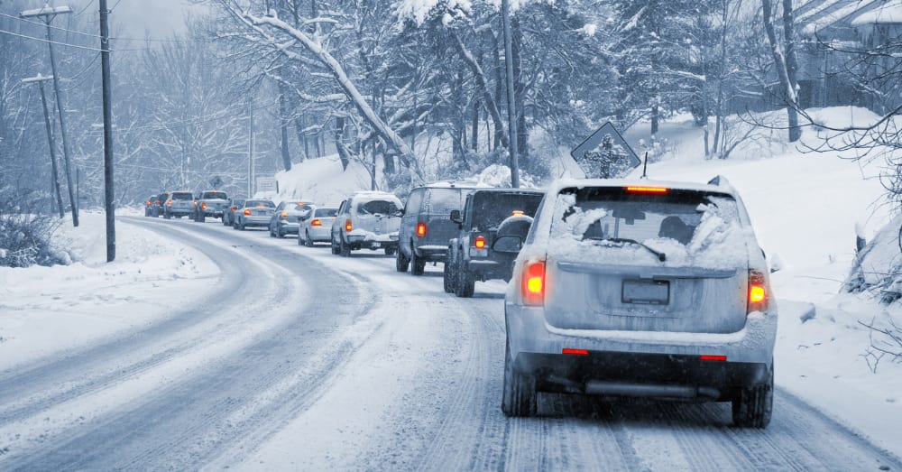 Vehicles driving through falling snow on a winter road