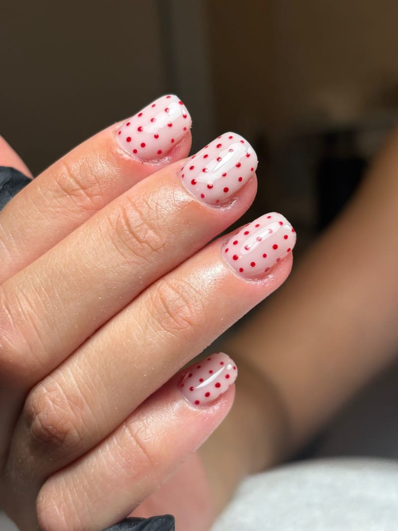Korte milky nagels met een patroon van kleine rode stippen