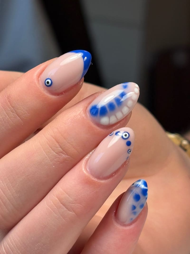 Nude nagels met kobaltblauwe tips, evil-eye details en witte stippen