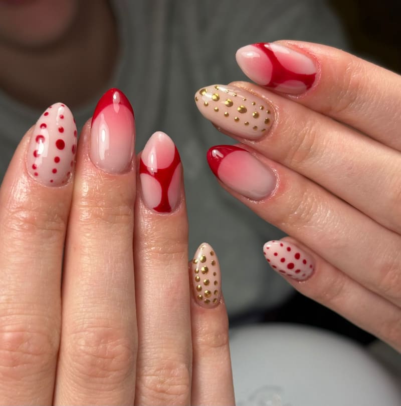 Set met rode swirls, rode stippen en gouden studs op nude nagels