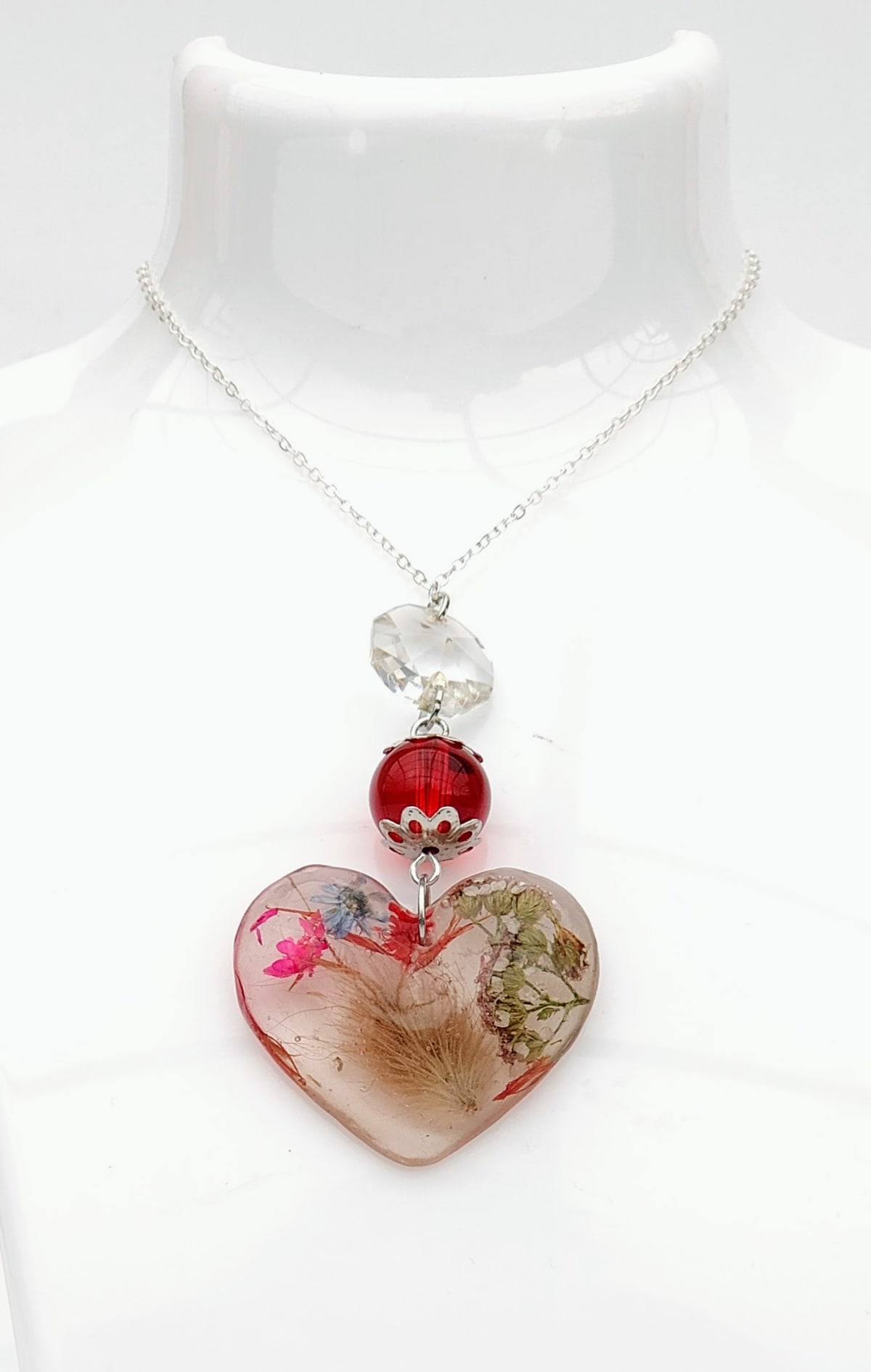 Laissez-vous séduire par ce collier fleurs résine et sa pampille perle d'un rouge éclatant. Une création artisanale unique, née de l'upcycling, pour porter la poésie de la nature au quotidien.