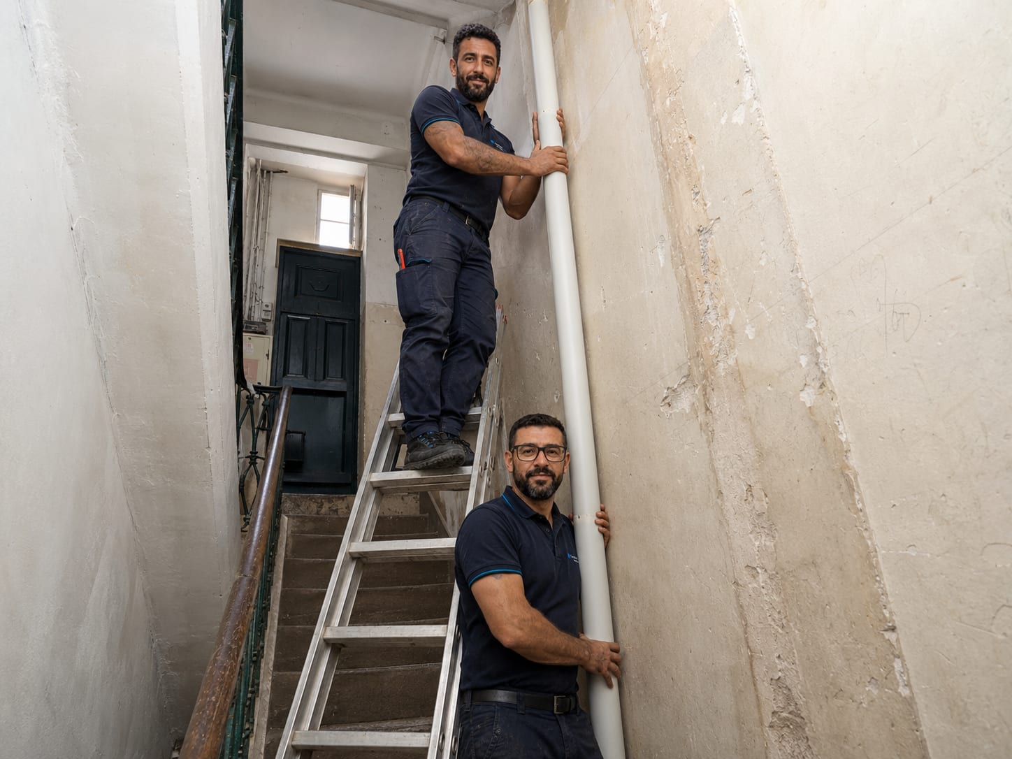 Técnico a substituir coluna vertical de ferro galvanizado por multicamada num prédio