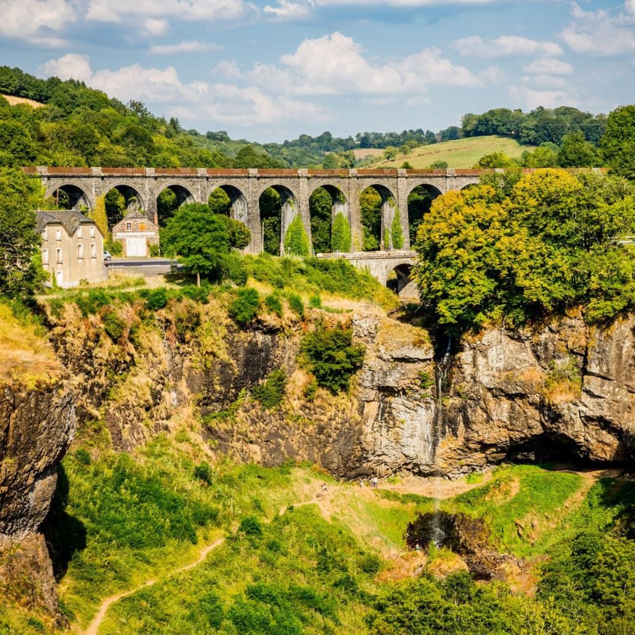 Randonnée cascade de Salins : filet d'eau chutant au loin sous viaduc, entouré de végétation et de roche