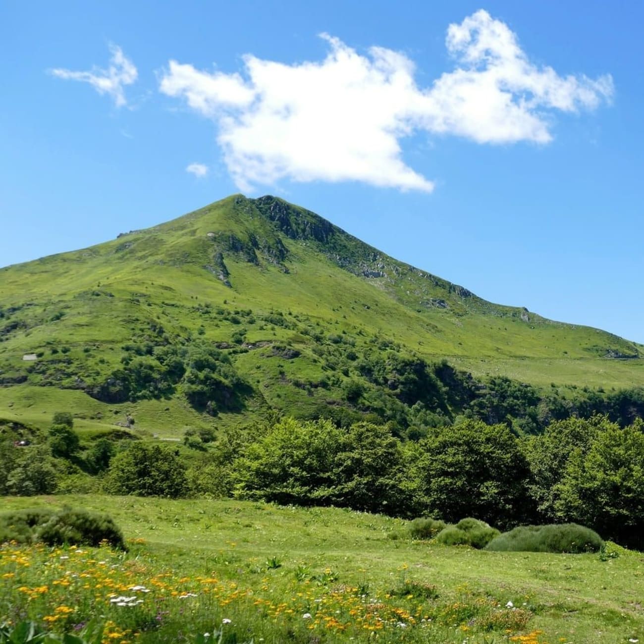 Randonnée monts du Cantal : mont verdoyant pointant vers le ciel bleu