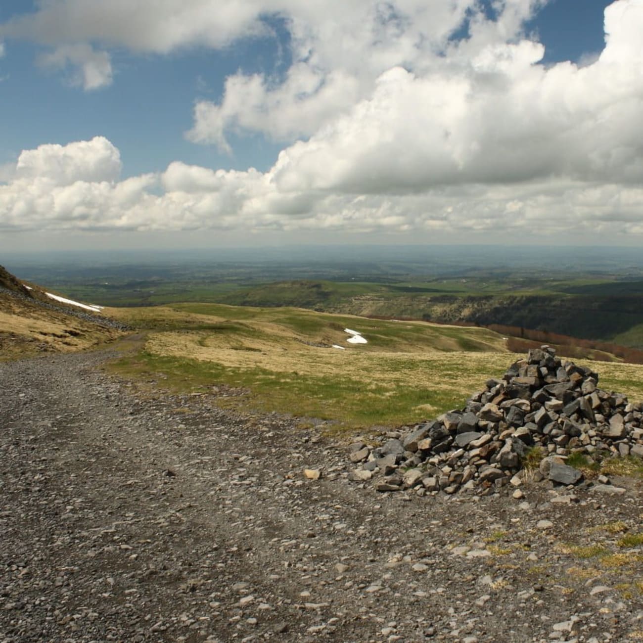 Randonnée monts du Cantal : sentier rocailleux en montagne et tas de pierres sur le côté