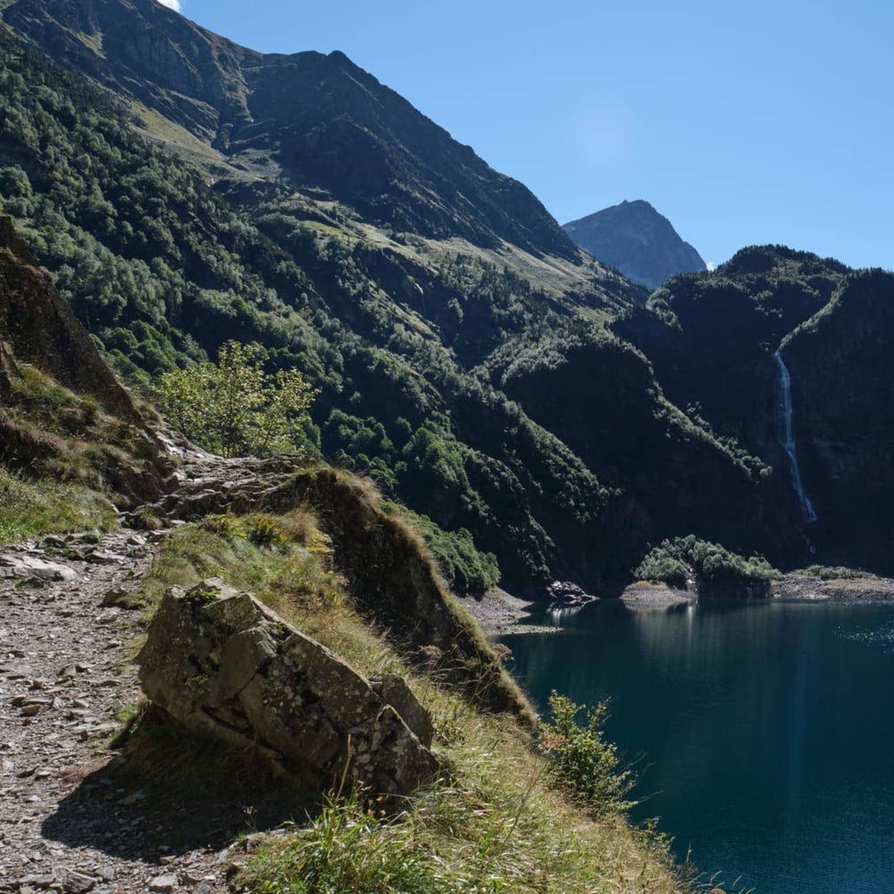 Randonnée lac d'Oô : sentier rocailleux au bord de l'eau