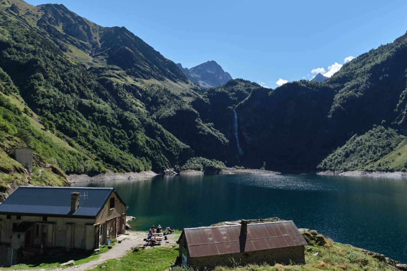 Randonnée lac d'Oô : bâtisses au bord d'un lac entouré de montagnes verdoyantes