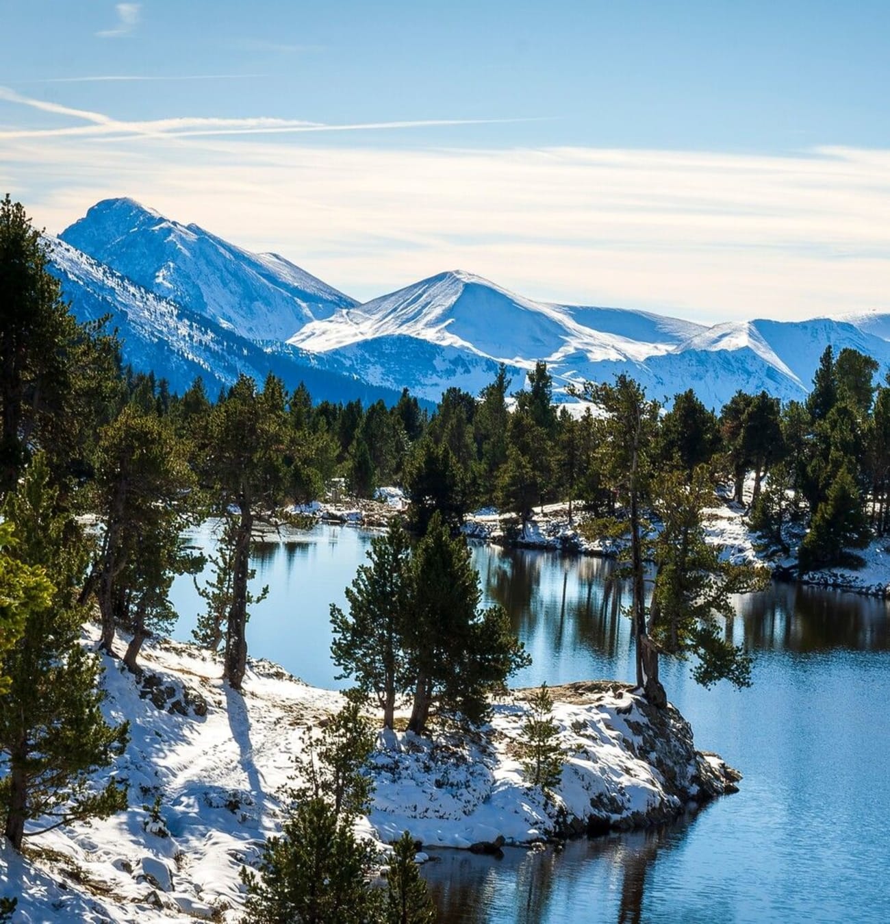 Photo du lac Achard en hiver avec ses rives et sapins enneigés.