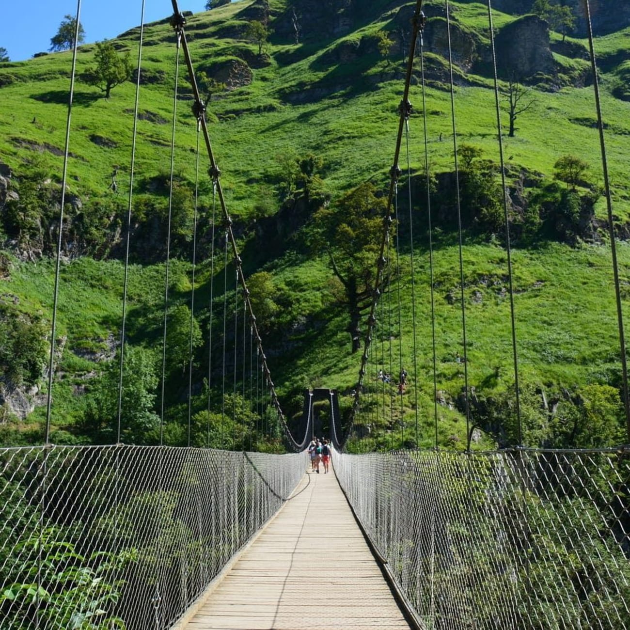 Randonnée passerelle d'Holzarte : personnes marchant sur pont suspendu au pied d'une montagne verdoyante