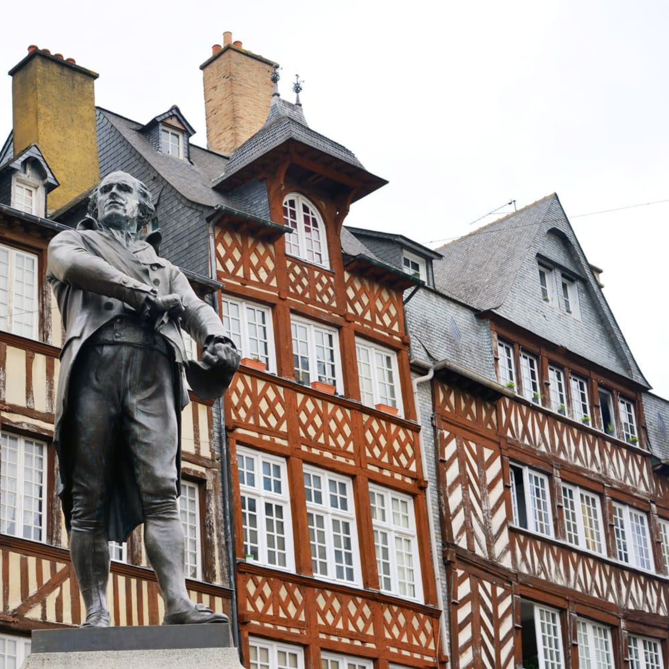 Balades Rennes : statue devant maisons à pans de bois rouges et ocres