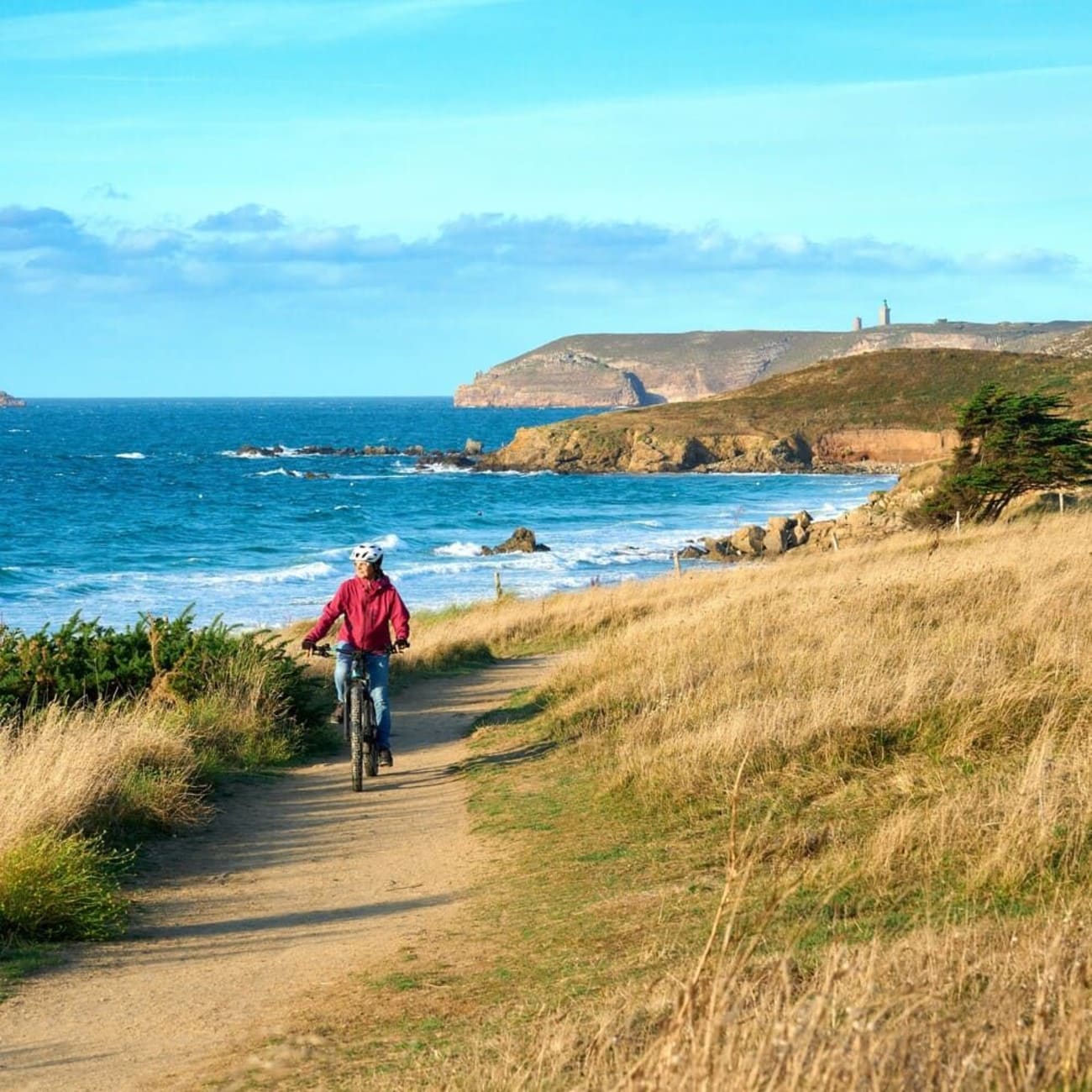 Vélo au cap Fréhel : cycliste sur un sentier avec le cap Fréhel en arrière plan